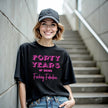 Woman wearing black ‘40 Years of Being Fucking Fabulous’ black birthday t-shirt, bold pink mixed-font lettering, confident and playful 40th birthday celebration vibe