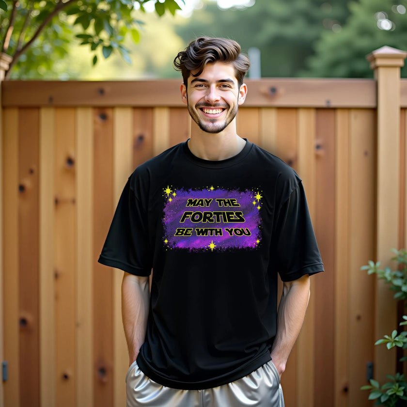 Man wearing ‘May the Forties Be With You’ black birthday t-shirt outdoors, retro yellow lettering on blue-purple galaxy background, playful and confident 40th birthday celebration vibe.