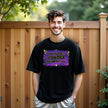Man wearing ‘May the Forties Be With You’ black birthday t-shirt outdoors, retro yellow lettering on blue-purple galaxy background, playful and confident 40th birthday celebration vibe.