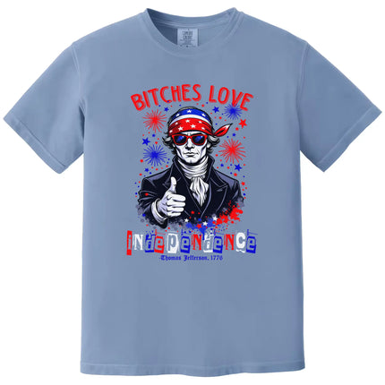 Patriotic Jefferson graphic tee in blue with ‘Bitches Love Independence’ text, sunglasses, bandana, and fireworks background for July 4th.