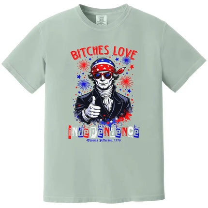 Bold Independence Day graphic tee in green featuring ‘Bitches Love Independence’ with Thomas Jefferson, sunglasses, bandana, and sparkles