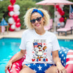 Female model wearing white ‘Just Here for the Wieners’ t-shirt outdoors, cute goose with flag and hot dog graphic, fun July 4th BBQ vibe