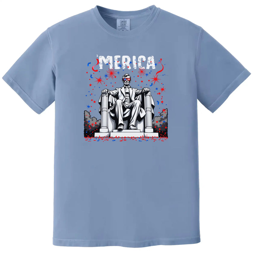 Patriotic Abraham Lincoln ‘Merica shirt in blue, bold fireworks design with Lincoln wearing flag sunglasses, funny Independence Day graphic tee.