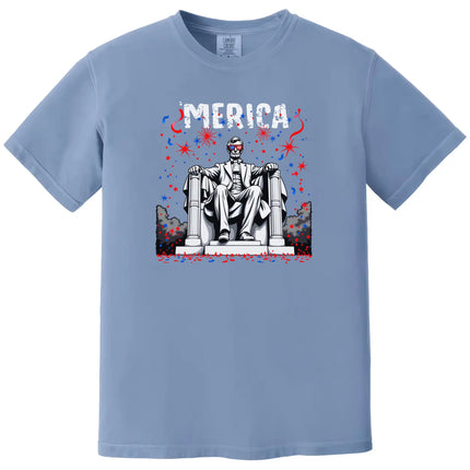Patriotic Abraham Lincoln ‘Merica shirt in blue, bold fireworks design with Lincoln wearing flag sunglasses, funny Independence Day graphic tee.