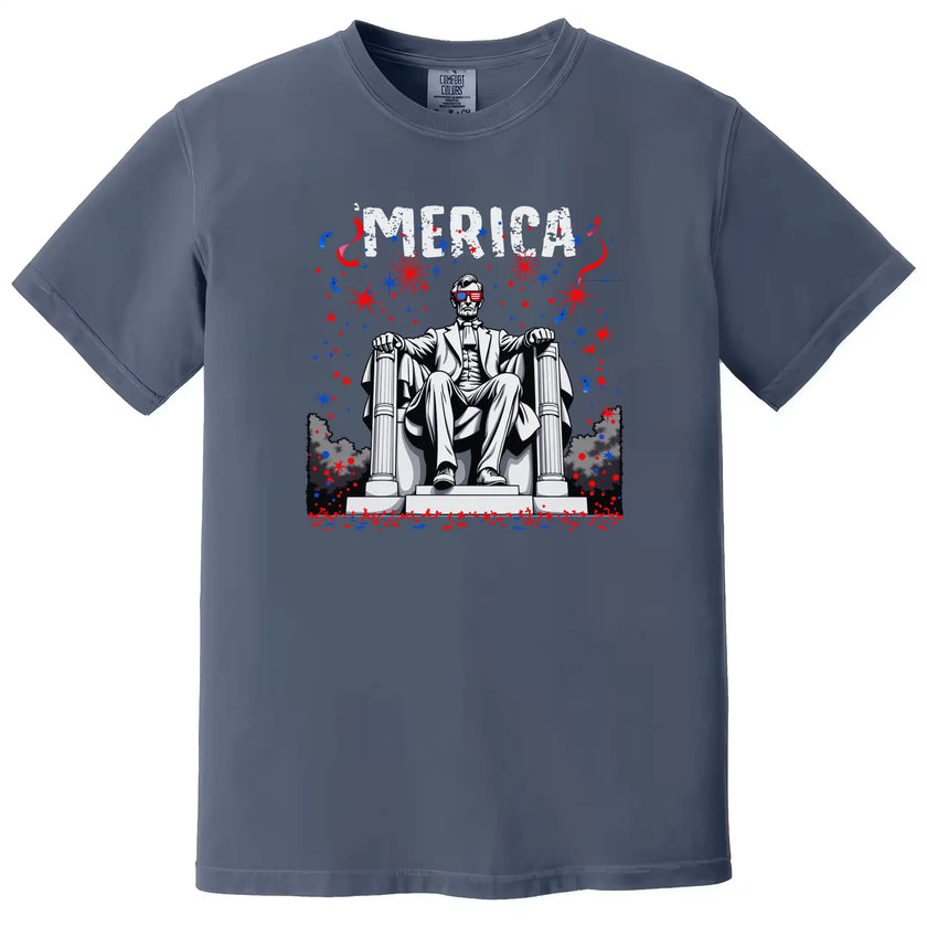 Patriotic ‘Merica t-shirt in dark blue, Abraham Lincoln with flag sunglasses and fireworks background, casual July 4th graphic tee.