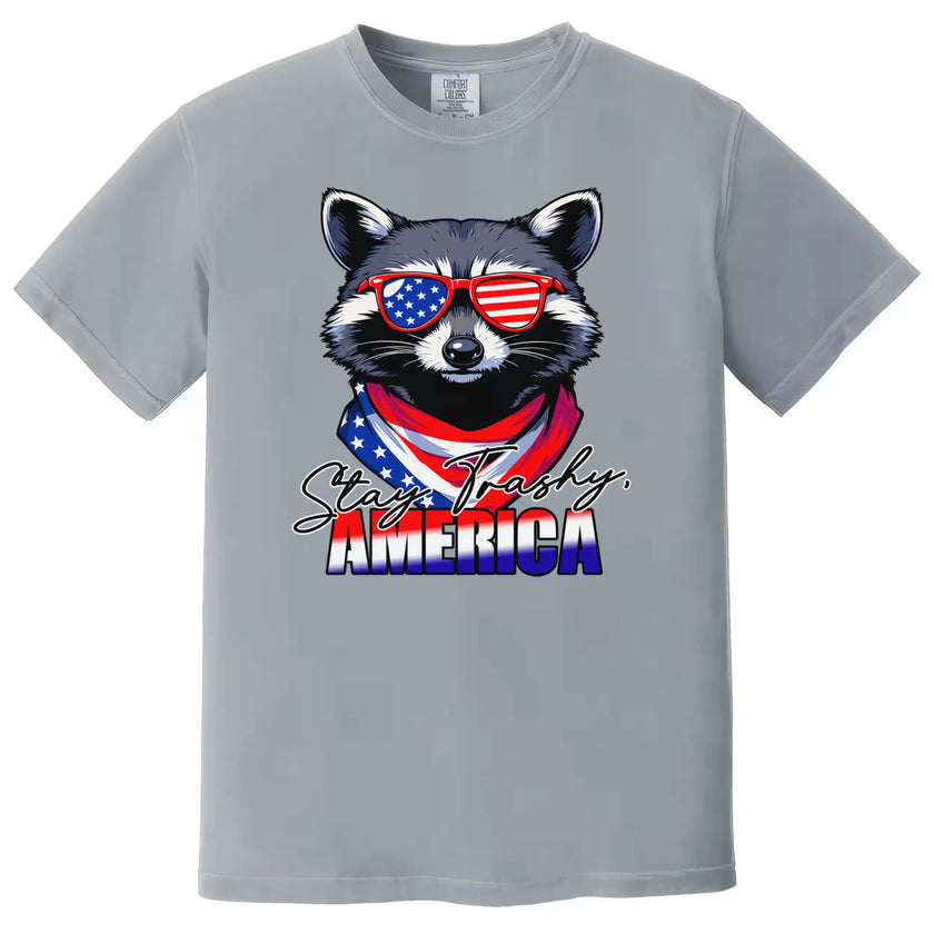Raccoon patriotic t-shirt in gray with ‘Stay Trashy America’ text, sunglasses and flag bandana design, humorous Independence Day shirt.