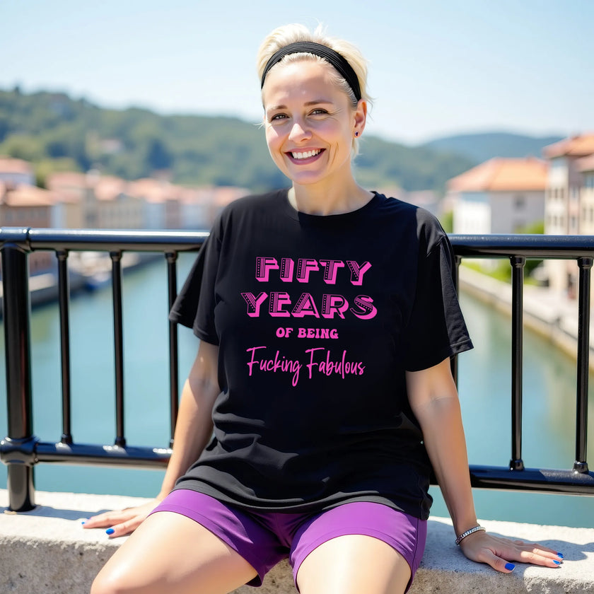 Woman wearing black ‘50 Years of Being Fucking Fabulous’ birthday t-shirt with bold pink mixed-font lettering, confident and playful 50th birthday celebration vibe.