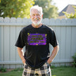 Man wearing ‘May the Fifties Be With You’ black birthday t-shirt outdoors in backyard, retro yellow lettering on galaxy background, celebrating 50th with confident, playful vibe.
