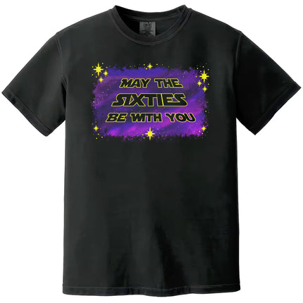 Black “May the Sixties Be With You” birthday t-shirt flat lay with bold retro galaxy font and purple blue starry space design