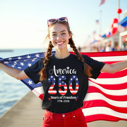 Female model wearing black America 250 years of freedom t-shirt outdoors, flag-filled 250 design with star sparkles, patriotic celebration vibe.