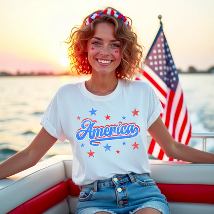 Model wearing white vintage ‘America’ t-shirt outdoors on boat, distressed red white blue lettering with star sparkles, classic patriotic summer vibe.