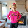 Female model wearing hot pink “Single AF” camouflage sweatshirt standing confidently in her living room, casual and playful vibe