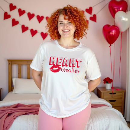 Woman wearing white Heartbreaker Valentine t-shirt in bedroom decorated for Valentine’s Day, cozy romantic aesthetic, playful love graphic tee