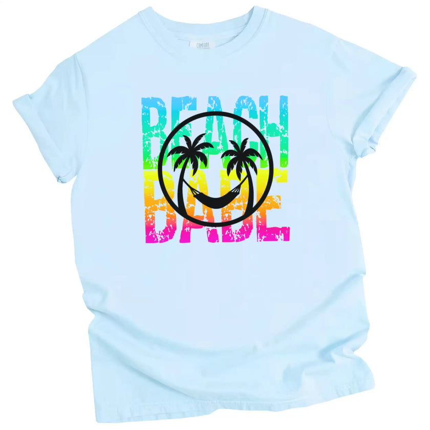 Beach Babe summer t-shirt in blue, neon rainbow distressed lettering with palm tree smile face and hammock design, tropical graphic tee.