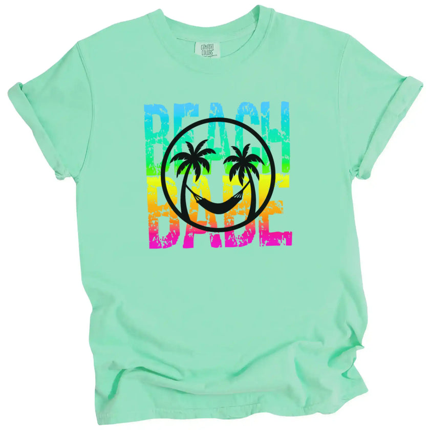 Beach Babe summer shirt in green, distressed neon rainbow lettering with tropical smile face and palm tree hammock design