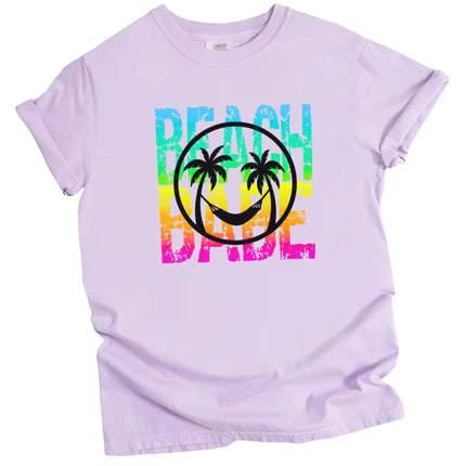 Beach Babe t-shirt in light purple, neon rainbow distressed lettering with beach smile face and palm tree graphic design.