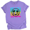 Beach Babe graphic t-shirt in purple, neon rainbow distressed lettering with tropical smile face and palm tree design.