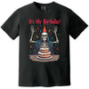 Black “It’s My Birthday” skeleton t-shirt flat lay with skeleton wearing party hat and cloak, surrounded by confetti, fun birthday tee