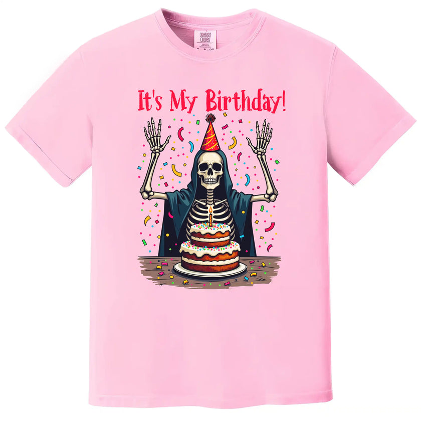 Pink “It’s My Birthday” skeleton t-shirt flat lay with cheerful skeleton, confetti, and party hat, fun and sarcastic birthday tee