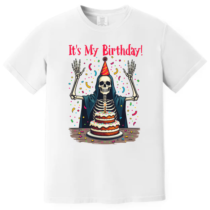 White “It’s My Birthday” skeleton t-shirt flat lay with party hat, cloak, and confetti design, playful and cheeky birthday graphic
