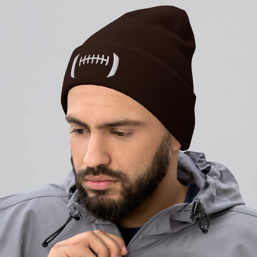 Man wearing a brown cuffed football beanie with distinctive white embroidered football-inspired design across the front, stylish winter hat for Buffalo football fans.