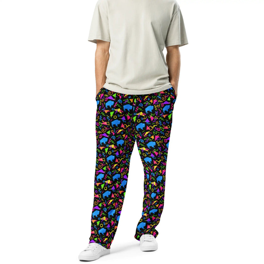 Man wearing Buffalo NY retro patterned pants with neon geometric print, colorful arcade-inspired shapes, and blue buffalo details in bold unisex style.