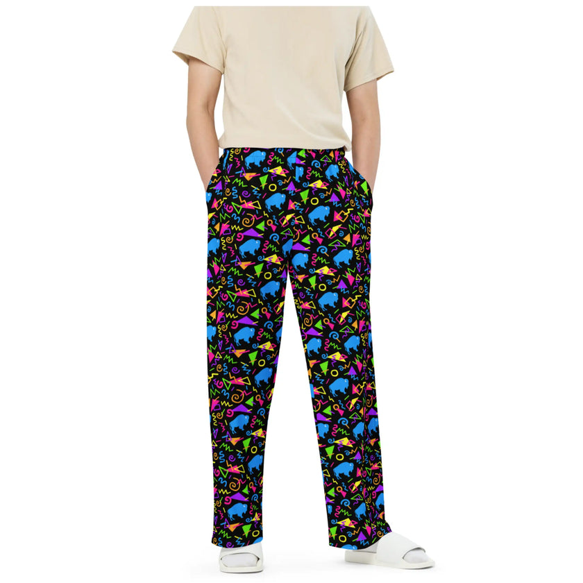 Man wearing Buffalo NY retro patterned pants with neon geometric print, colorful arcade-inspired shapes, and blue buffalo details in bold unisex style.