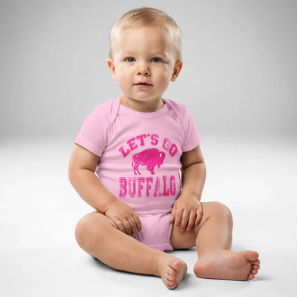 Baby wearing pink Buffalo football ‘Let’s Go Buffalo’ bodysuit with distressed hot pink lettering and buffalo silhouette graphic, front view.