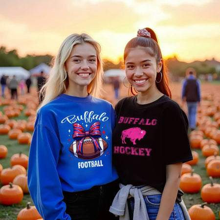 Two young women at pumpkin patch wearing Buffalo football sweatshirt and Buffalo hockey t-shirt at sunset, fall Buffalo sports apparel and game day fashion scene.