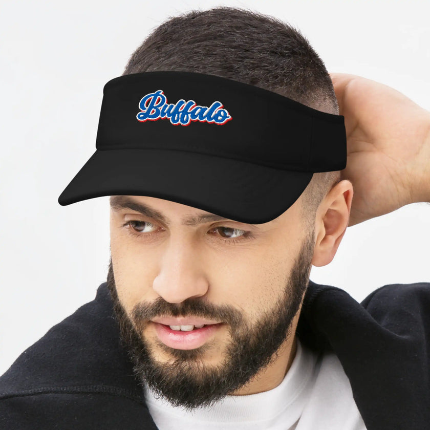 Man wearing a black Buffalo golf visor with bold embroidered Buffalo lettering in red white and blue, classic athletic style for golf, recreation, and Buffalo fans.