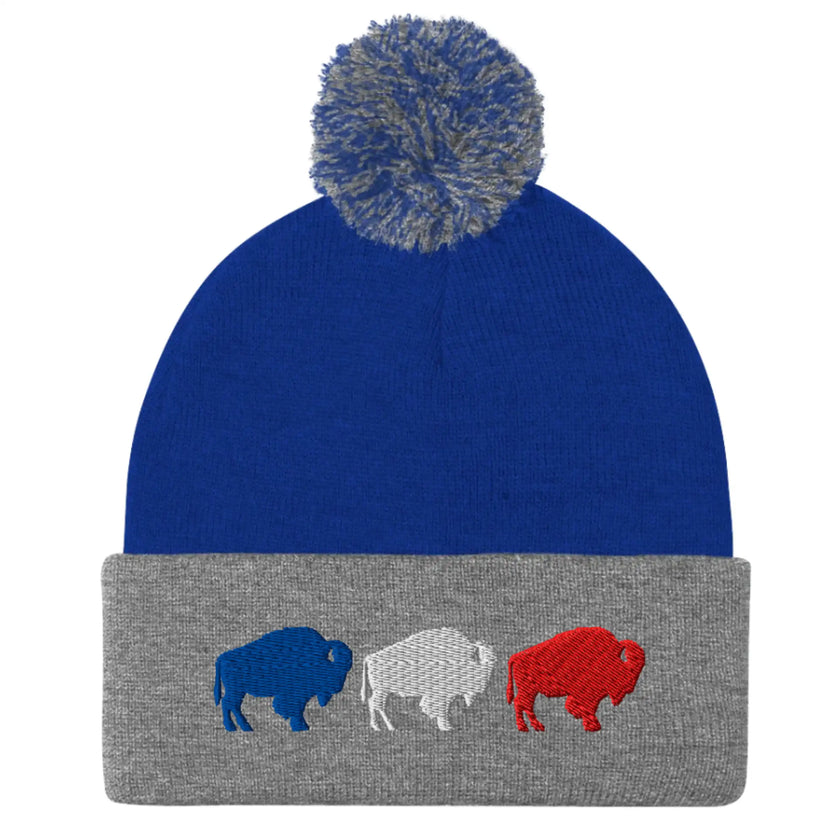 Blue and grey pom pom winter beanie featuring embroidered red white and blue Buffalo football trio silhouettes, Buffalo themed winter hat design.