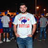 Man wearing white Let’s Go Buffalo football t-shirt at a nighttime tailgate party, showing football fan energy and Buffalo pride.