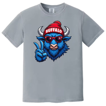 Light gray Buffalo pride t-shirt featuring blue buffalo with winter hat and peace sign, flat lay on white background.