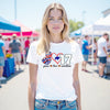 Woman wearing white Peace Love 17 t-quarterback shirt at a Buffalo street festival, showing football pride and city spirit.