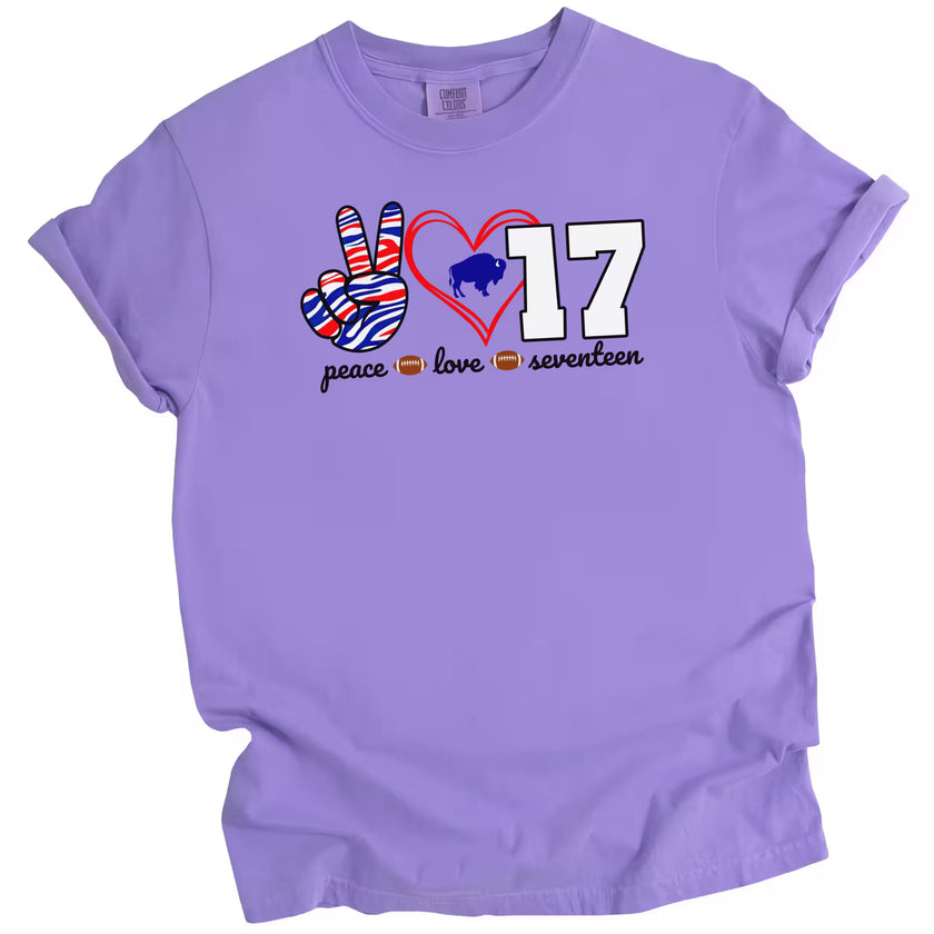 Peace Love 17 football quarterback t-shirt with striped peace sign, red heart, and white number graphic, purple tee flat lay on white background.