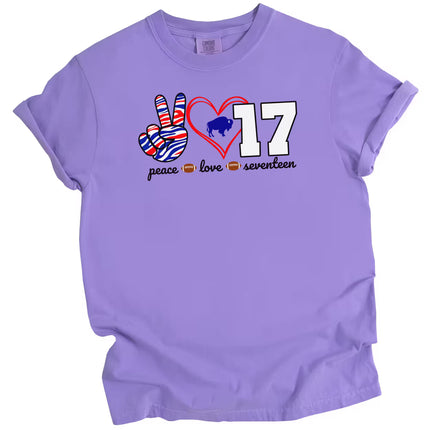 Peace Love 17 football quarterback t-shirt with striped peace sign, red heart, and white number graphic, purple tee flat lay on white background.