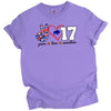 Peace Love 17 football quarterback t-shirt with striped peace sign, red heart, and white number graphic, purple tee flat lay on white background.