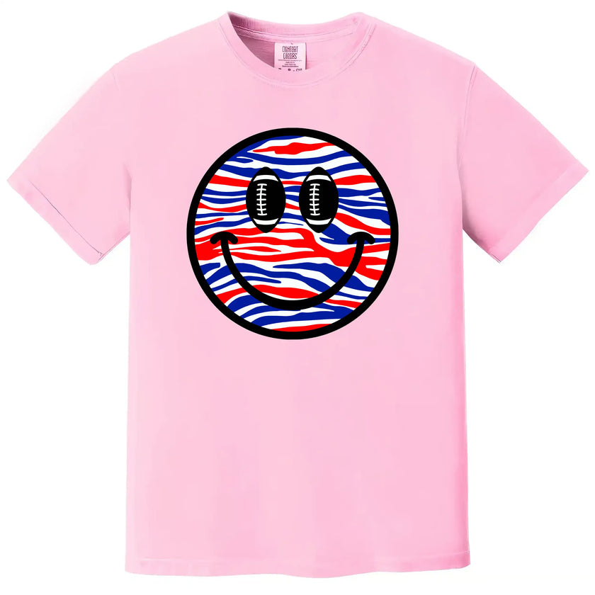 Football fan smiling face t-shirt in pink, Buffalo-inspired red white blue pattern with football eyes, playful game day graphic tee.