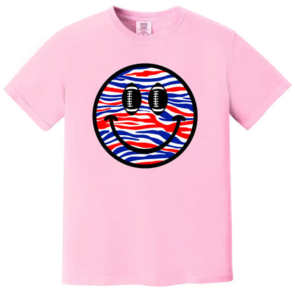 Football fan smiling face t-shirt in pink, Buffalo-inspired red white blue pattern with football eyes, playful game day graphic tee.