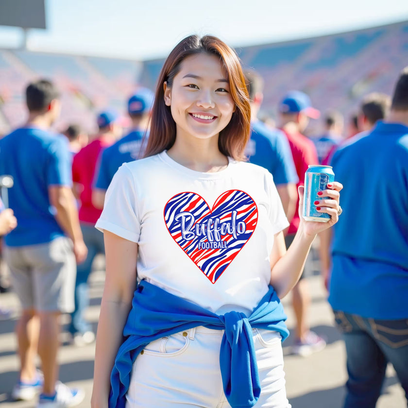 Woman wearing white Buffalo football t-shirt with striped heart graphic, standing on football field showing team pride.