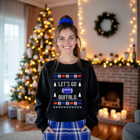 Woman standing in living room in front of Christmas tree wearing black Buffalo football ugly Christmas sweatshirt with ‘Let’s Go Buffalo’ knitted-style lettering, red and blue buffalo graphics, and blue football design.