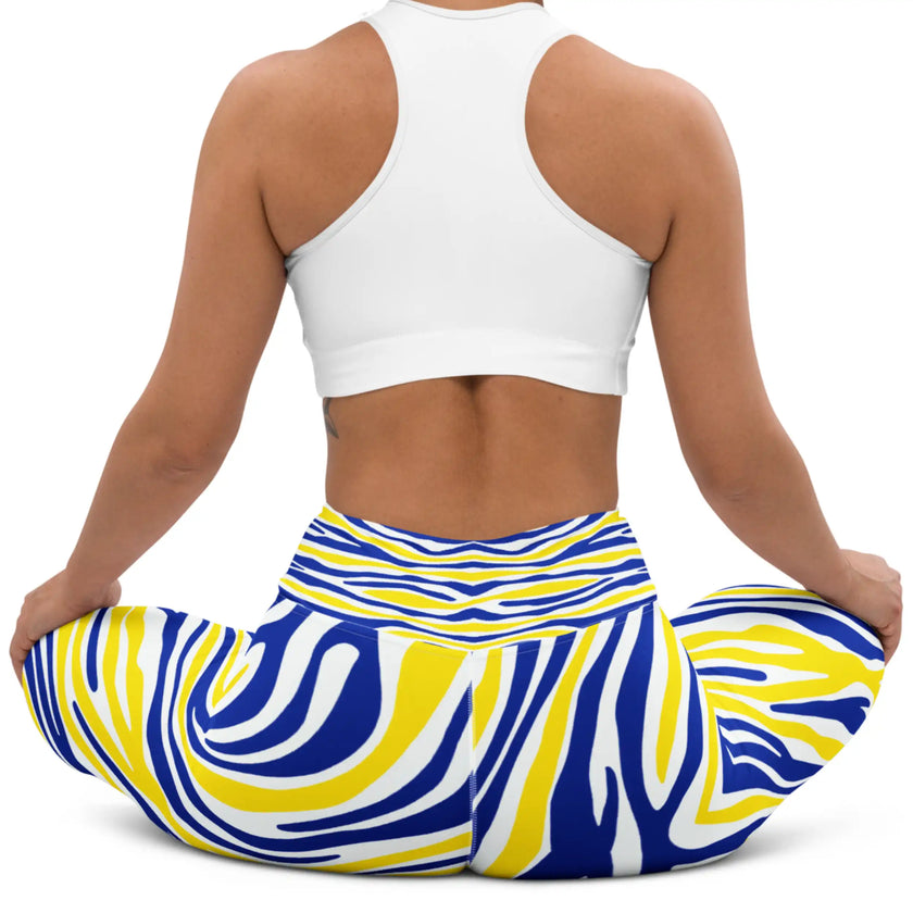 Woman sitting in blue and gold Buffalo hockey leggings, showing the flexible fitted design and colorful stripe pattern in a relaxed pose