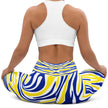 Woman sitting in blue and gold Buffalo hockey leggings, showing the flexible fitted design and colorful stripe pattern in a relaxed pose