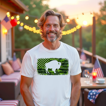 Male model wearing white Buffalo camo flag t-shirt, green camouflage American flag with distressed edges and buffalo cutout, patriotic casual look.