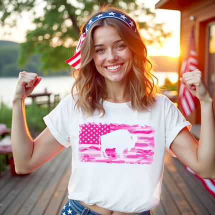 Female model wearing white Buffalo pink camo flag t-shirt, distressed American flag with buffalo cutout design, bold patriotic casual look.