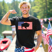 Male model wearing black Buffalo patriotic t-shirt outdoors, American flag design with buffalo silhouette cutout, casual summer July 4th Buffalo pride vibe