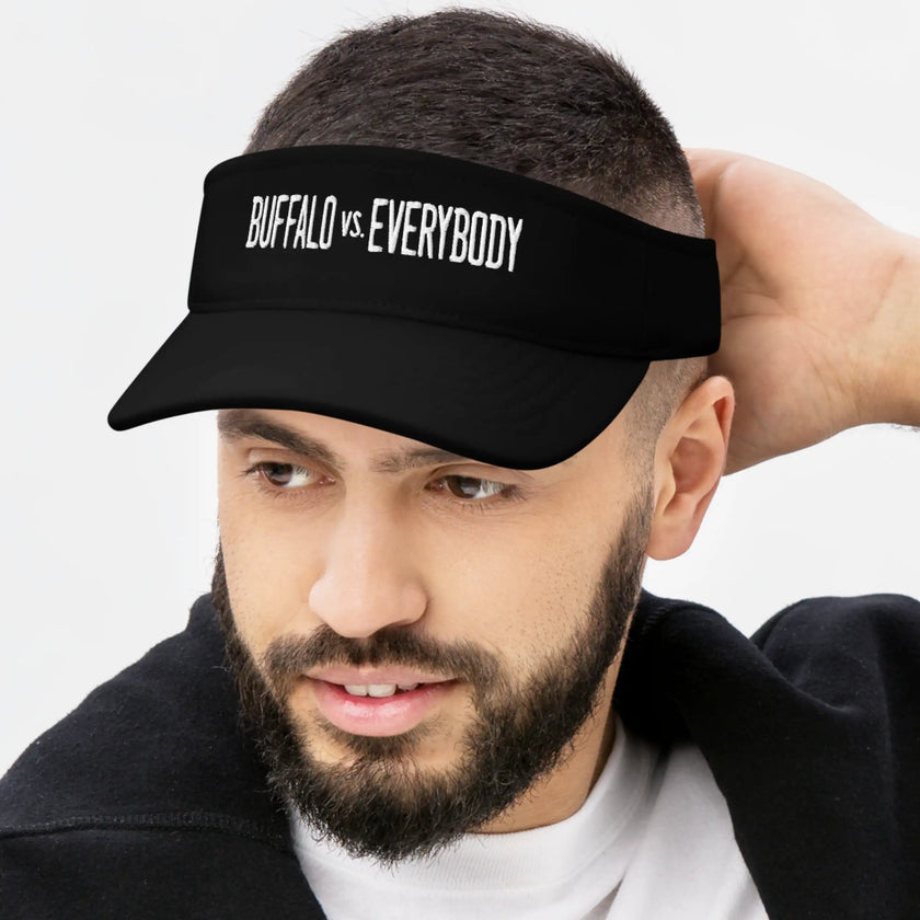 Man wearing a black Buffalo football golf visor with bold white embroidered ‘Buffalo vs. Everybody’ lettering, athletic fan style for the golf course or outdoors.