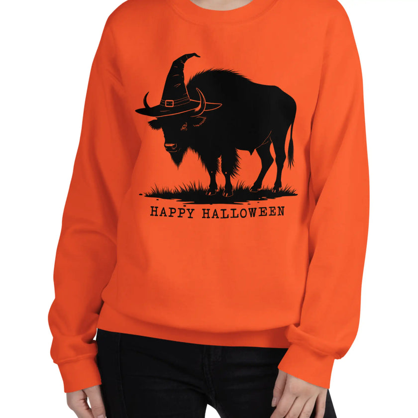 Woman wearing an orange Buffalo Halloween sweatshirt with a playful black buffalo wearing a witch hat graphic, festive fall fashion inspired by Buffalo NY.