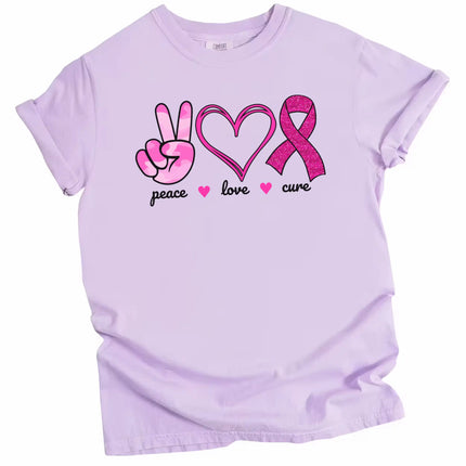 Purple “Peace, Love, Cure” t-shirt flat lay featuring pink peace hand, double-heart, and glittery ribbon icons with uplifting cause message