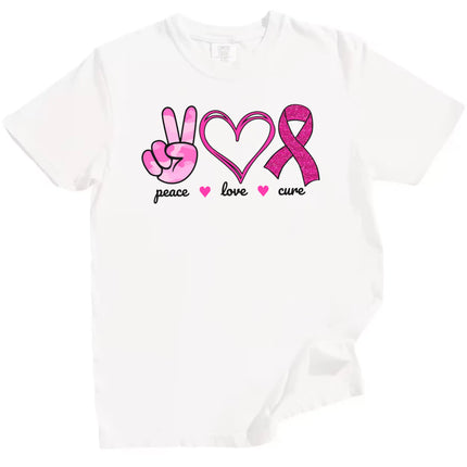 White “Peace, Love, Cure” t-shirt flat lay highlighting pink icons—peace hand, hearts, glitter ribbon—for breast cancer awareness and support